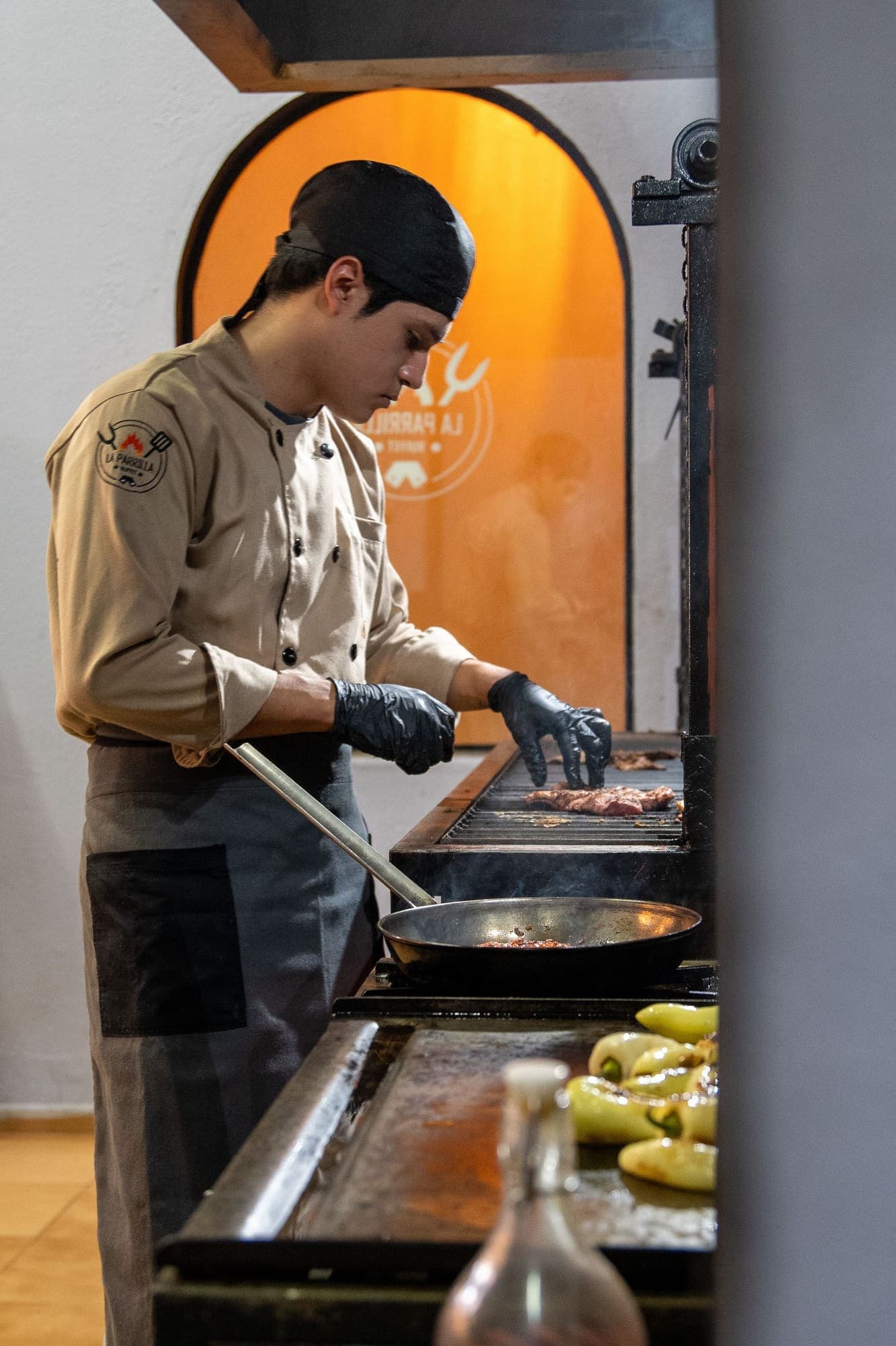 Cocinero prepara carne en la parrilla de la cocina de su restaurante